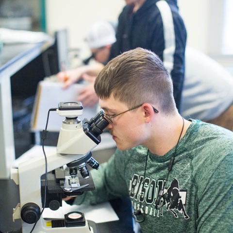 student looking through a microscope