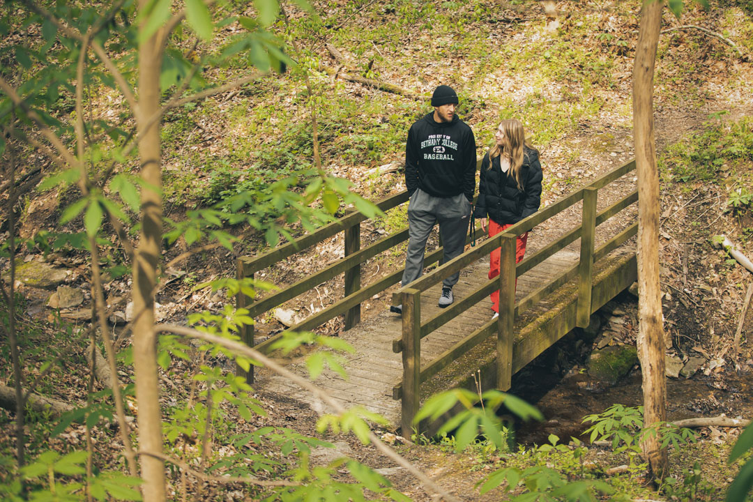 students talking on hiking path bridge